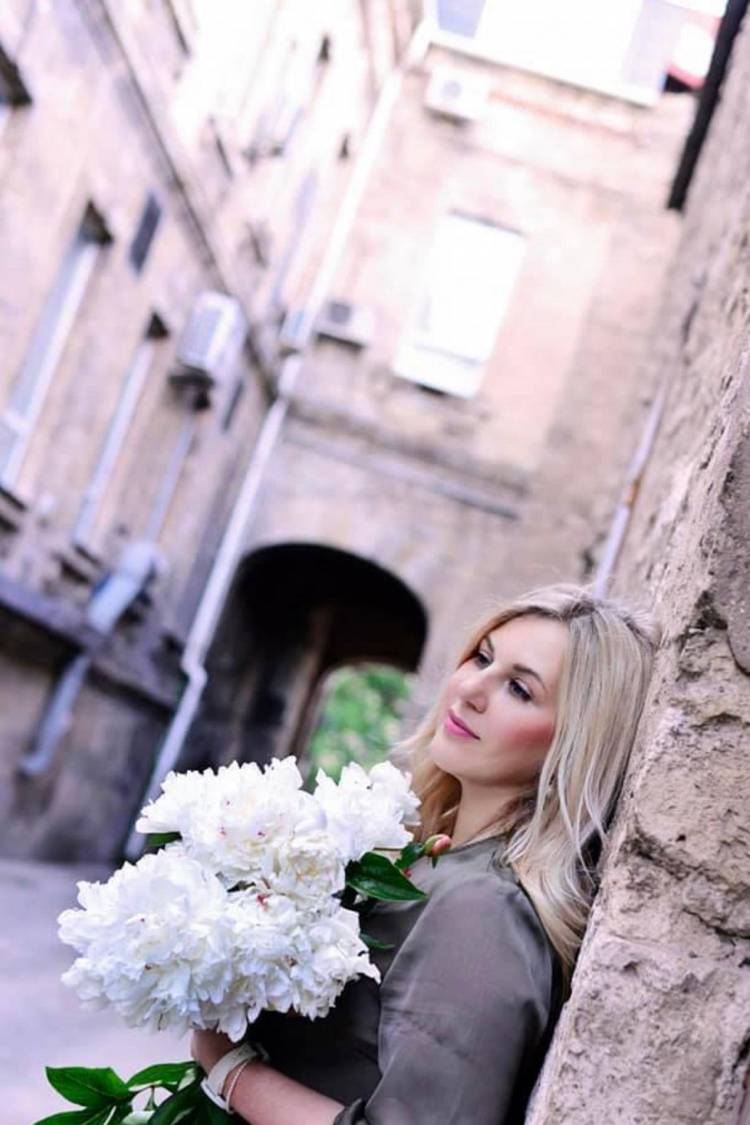 Attraktive Blonde Frau mit Blumen auf der Straße