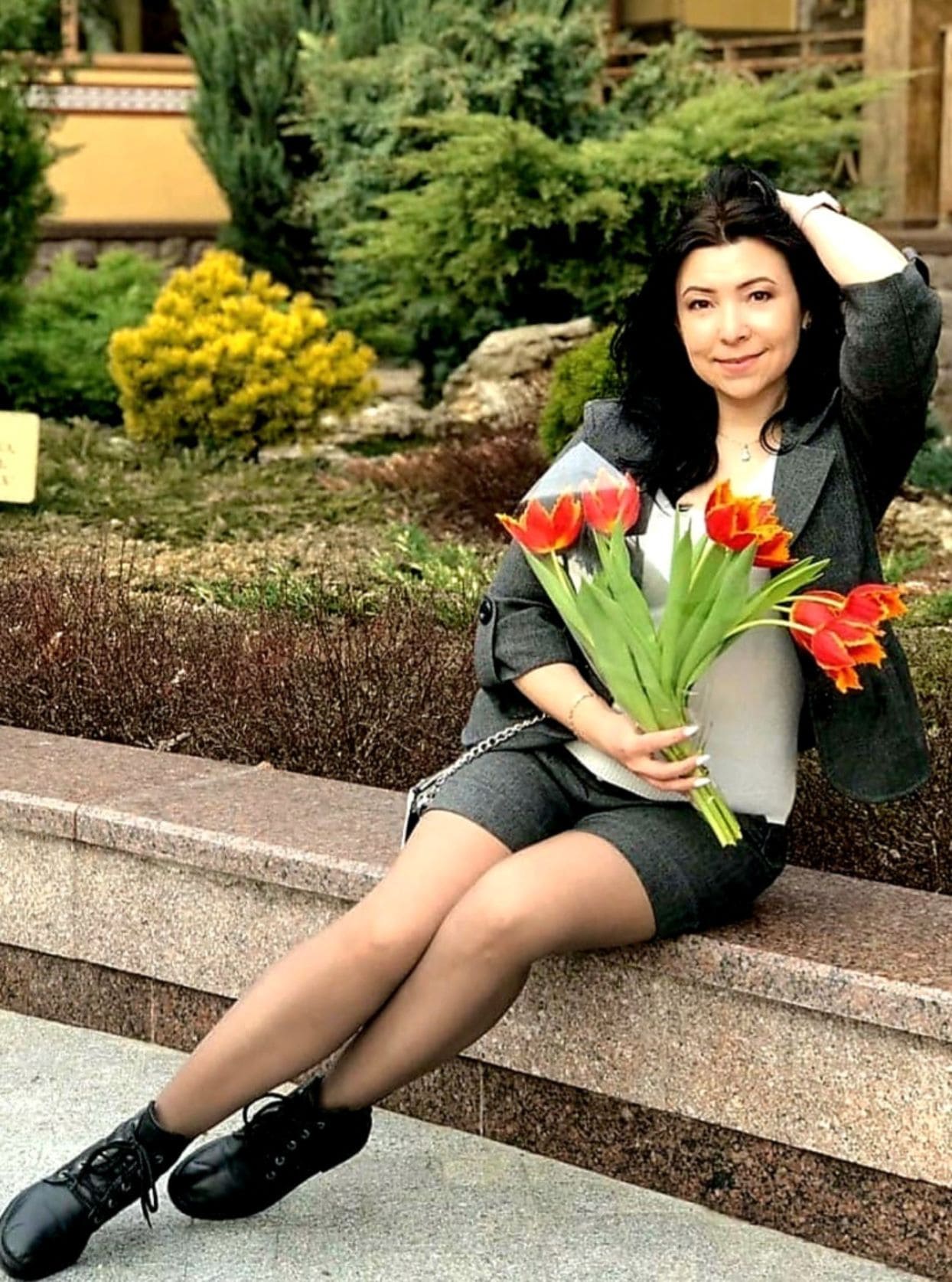 Luda sitzt mit Blumen auf der Bank.